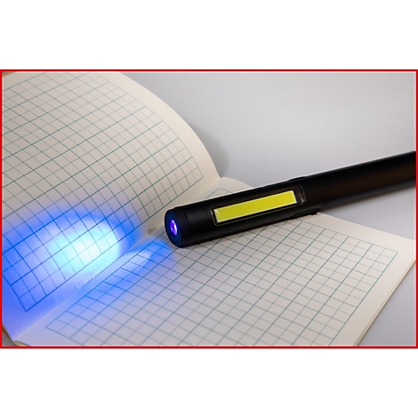 Zwarte penlamp die een open geruit notitieboekje verlicht. Het licht schijnt blauw.